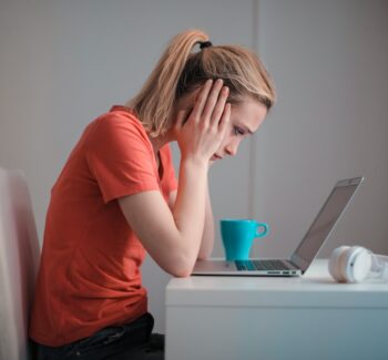 Young troubled woman using laptop at home thinking about quitting teaching